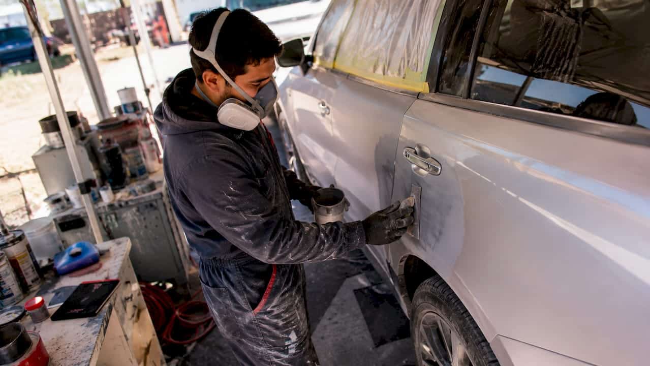 Technician applying primer in auto body workshop