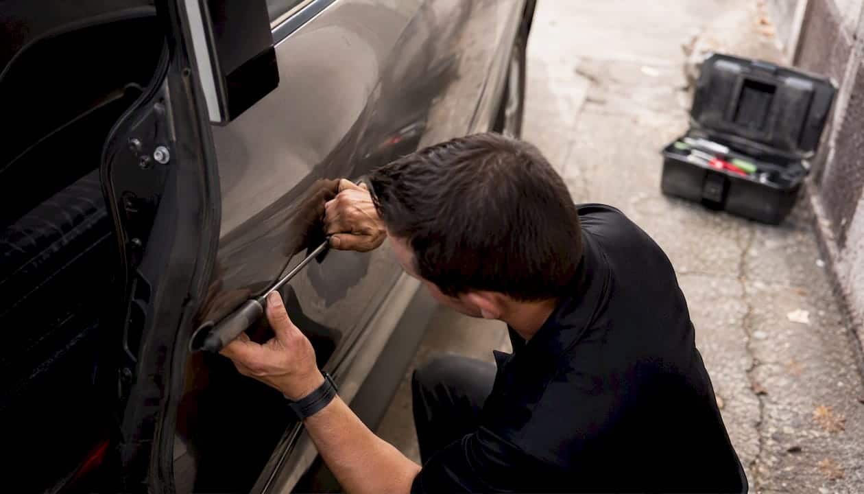 Technician repairing car dent with specialized tools