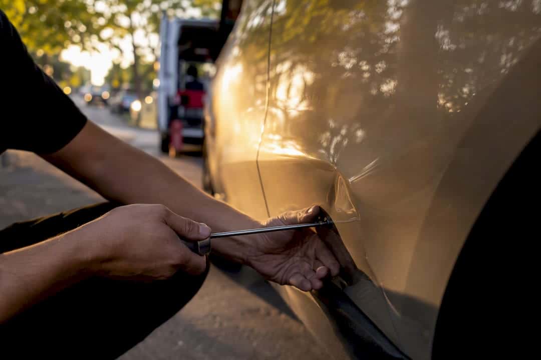 Technician performing paintless dent repair on car panel