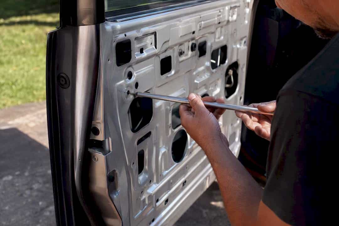 What Does Paintless Dent Repair Cost in 2026? 3 Hands Repairing Aluminum Truck Door Dent