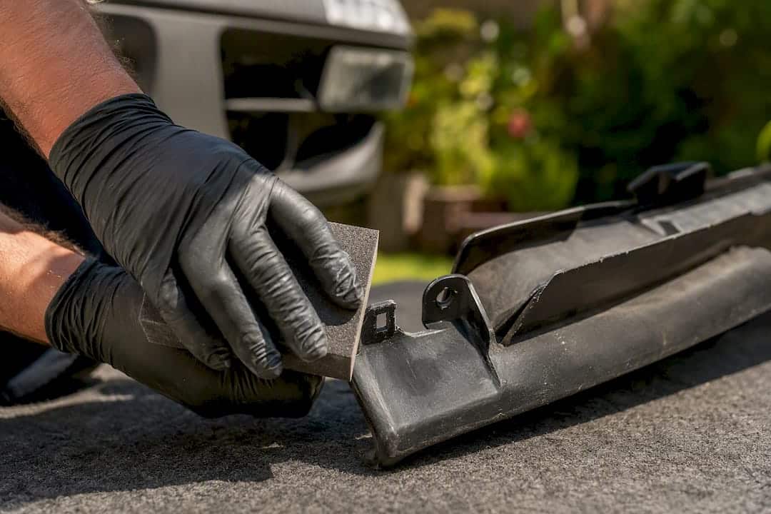 Hands sanding and prepping broken bumper tab
