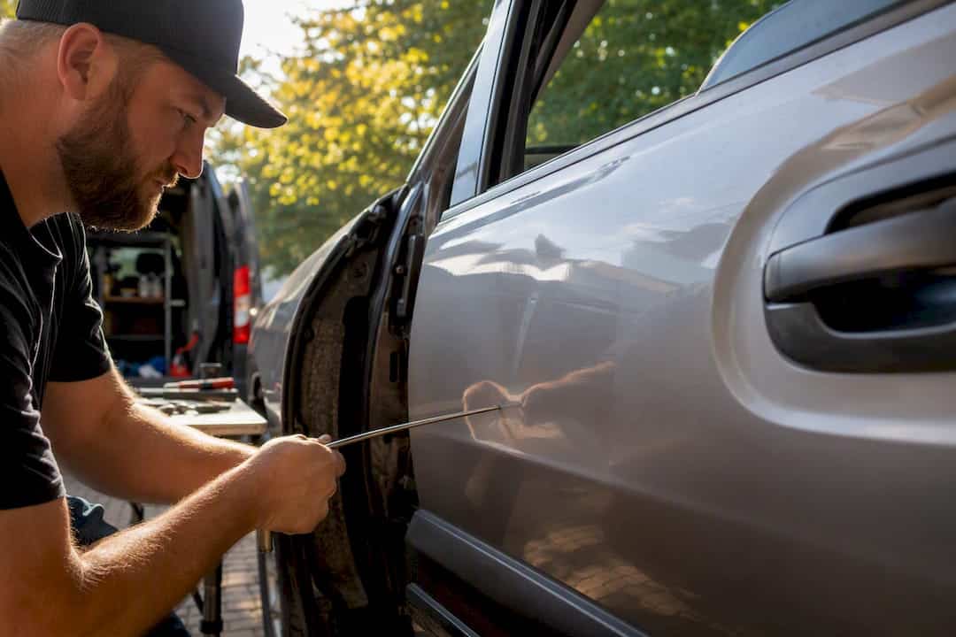 Hands repairing door crease dent with tools