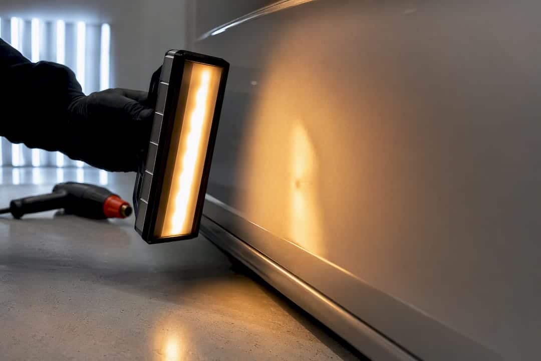 Avoid Cracked Paint: PDR in Cold Weather for Car Owners 1 Infrared Lamp Warming A Dented Panel
